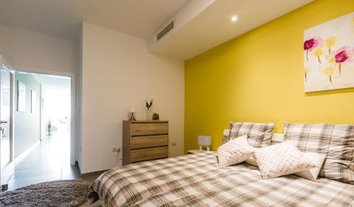 a bedroom with a bed and a yellow wall at Splendid Seaside Retreat on Spinola Bay in St. Julianʼs