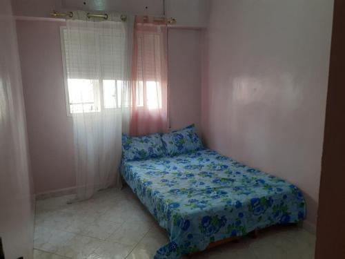 a bedroom with a bed with blue sheets and a window at Appartement Sidi Maarouf in Casablanca