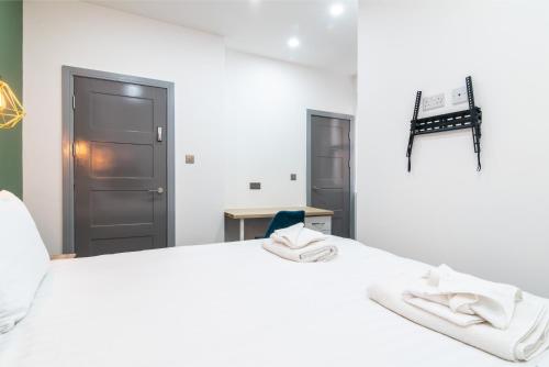 een wit bed met witte handdoeken erop bij Charnwood Flat 4 - City Center 3BR Gem in Derby