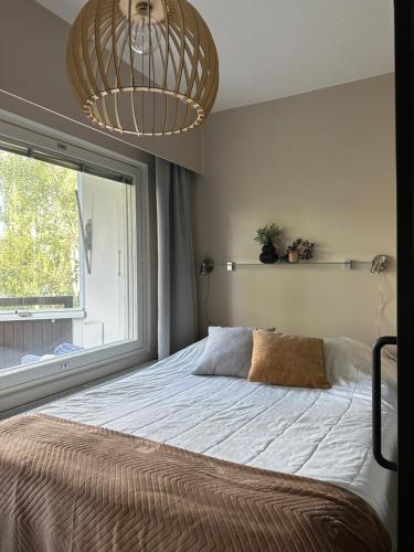 Schlafzimmer mit einem Bett mit einem Fenster und einem Kronleuchter in der Unterkunft Snowest Travels - City Home ll in Rovaniemi