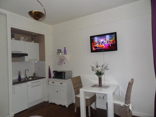 a kitchen with a small white table and a tv on the wall at Studio Maison Fyot in Dijon