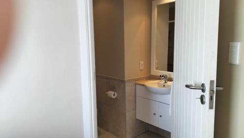 ein Badezimmer mit Waschbecken und Spiegel in der Unterkunft Port Apartment with Sea Views in St Francis Bay