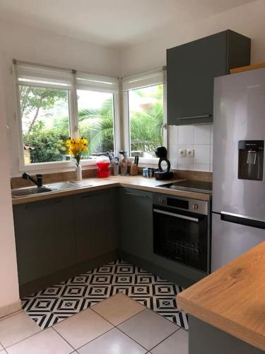 une cuisine avec un réfrigérateur en acier inoxydable et un évier dans l'établissement A deux pas du port, jolie maison redécorée, à La Teste-de-Buch