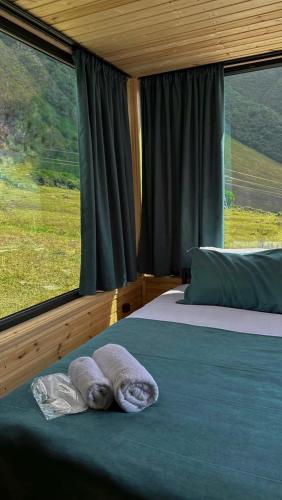 a bedroom with two beds and a large window at Kazbegi Inn Cottages in Stepantsminda