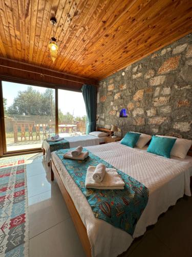 two beds in a room with a stone wall at Kabak Armes Hotel in Faralya