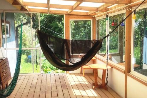 a hammock in a screened in porch with windows at Simple life in Gothenburg