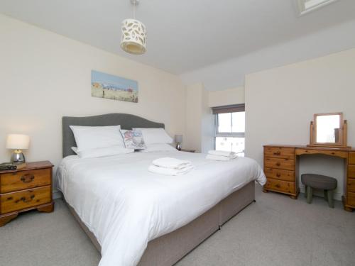 a bedroom with a large white bed and a desk at Pass the Keys Spacious Cottage in central Benllech with parking in Benllech
