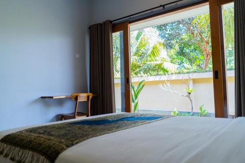 a bedroom with a bed and a large window at Buda's Guesthouse in Tanah Lot