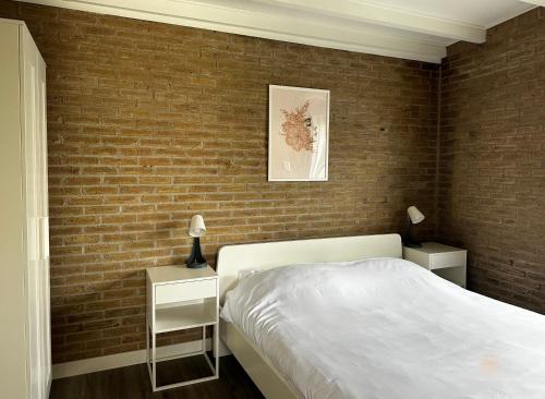 a bedroom with a brick wall and a bed at -Casa Nova- nabij het meer, duinen en restaurants in Noordwijkerhout