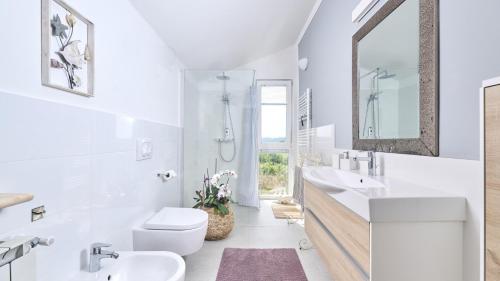 - une salle de bains blanche avec deux lavabos et un miroir dans l'établissement Apartment Dajana, à Novigrad