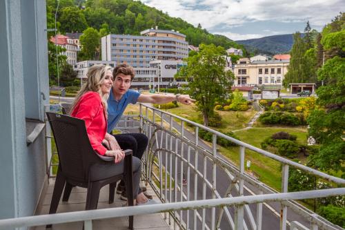 a man and a woman sitting on a balcony at Hotel Astoria in Jáchymov