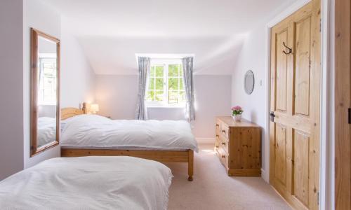 a bedroom with two beds and a mirror at See the llamas at a beautiful Somerset Cottage in Combe Saint Nicholas