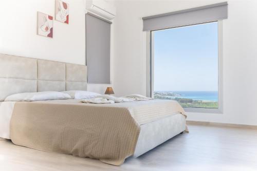 um quarto branco com uma cama grande e uma janela grande em Villa Aqua Queen em Coral Bay