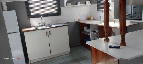 uma cozinha com armários brancos e um lavatório em Rato Thato Guest House em Durban