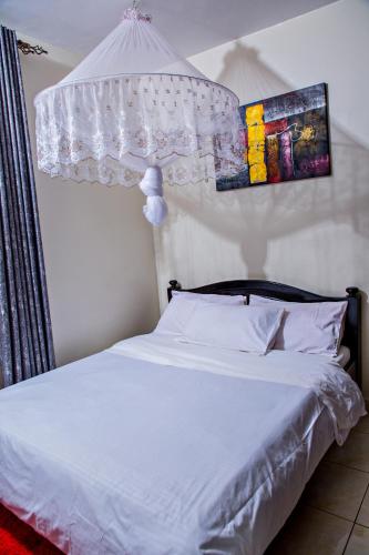 a bedroom with a white bed and a chandelier at One bedroom apartment at Nalya in Kampala