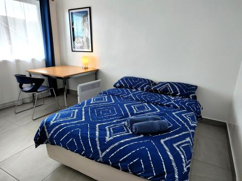 a bedroom with a bed with a blue comforter and a table at PROMO!!! 2-Bedroom Home Near Airport, Train Station! in Melbourne