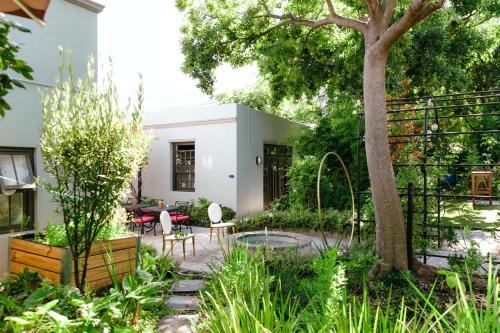 a garden with a tree and a table and chairs at La Fontaine Boutique Hotel by The Oyster Collection in Franschhoek
