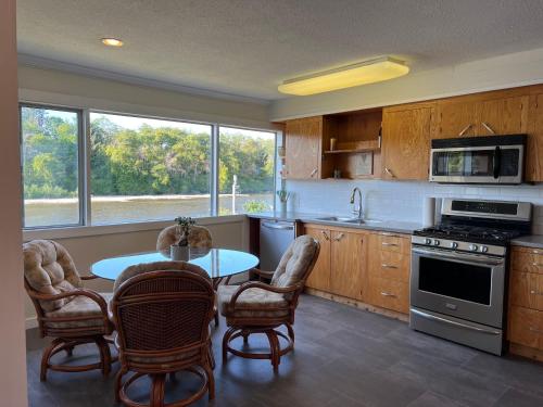 een keuken met een tafel en stoelen en een keuken met een raam bij River house in Campbell River