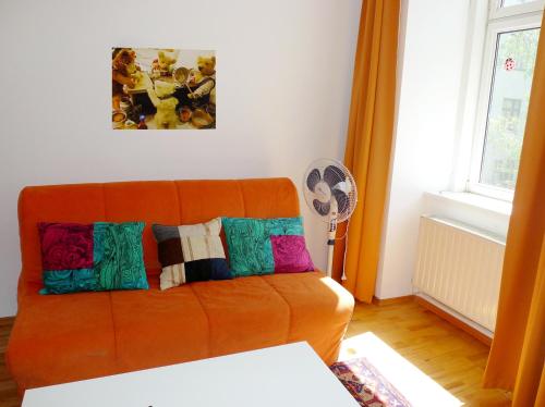 an orange couch with colorful pillows in a living room at Apartment Messe in Vienna