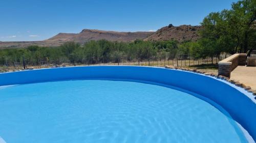 una grande piscina blu con montagne sullo sfondo di Ruigtevallei Lodge a Gariepdam