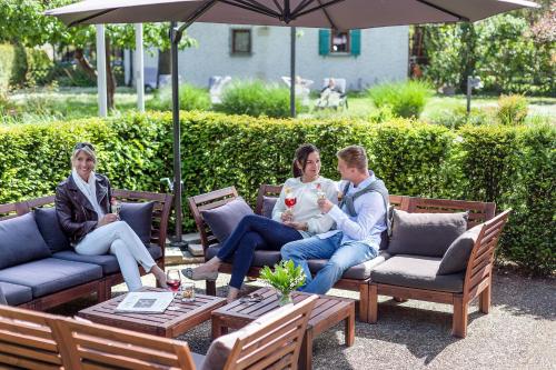 a group of people sitting on chairs under an umbrella at Ganter Hotel & Restaurant Mohren in Reichenau