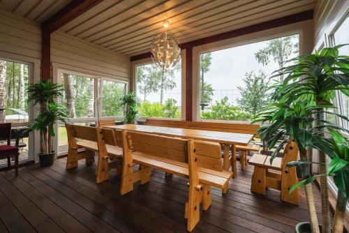 un comedor con una larga mesa de madera y ventanas en Senelio Romo Sodyba, en Molėtai