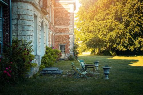 two chairs and a table in the yard of a house at Chambres d'hôtes & Gîtes du Château de Grand Rullecourt in Grand Rullecourt
