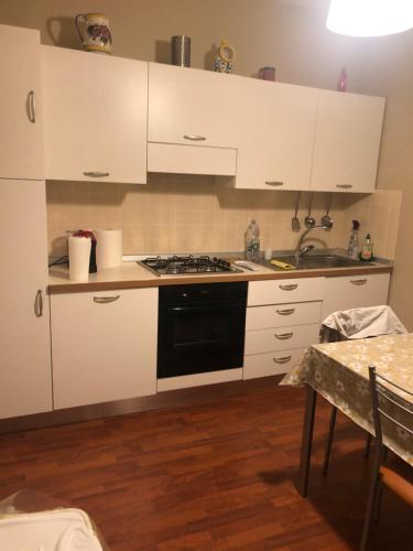 uma cozinha com armários brancos e um forno com placa de fogão em Casa Carly em Macchia