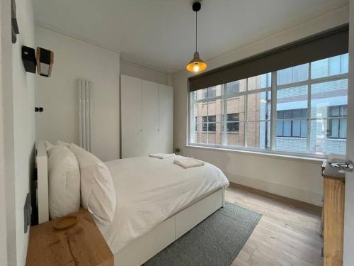 ein Schlafzimmer mit einem weißen Bett und einem großen Fenster in der Unterkunft Stylish city-centre apartment with balcony in Liverpool