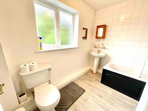 a white bathroom with a toilet and a sink at Large 5 bed detached house near Stansted Airport in Stansted Mountfitchet