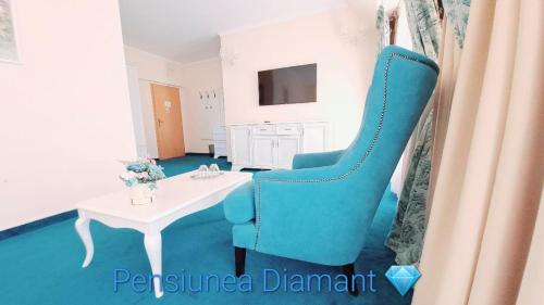 a blue chair and a table in a room at Pensiunea Diamant in Ghimbav