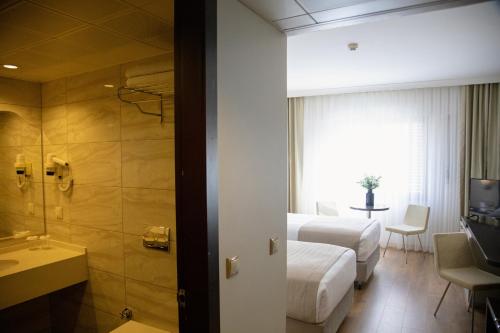 een hotelkamer met twee bedden en een badkamer bij Kaya Prestige Oteli in Izmir