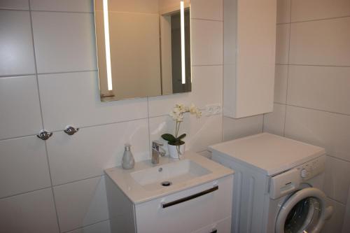 ein weißes Badezimmer mit einem Waschbecken und einem Spiegel in der Unterkunft Sprotte in Schönberger Strand