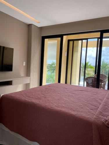 a bedroom with a bed and a tv and windows at Apartamento Alto Padrão 3 quartos Iberostate Praia do Forte in Praia do Forte