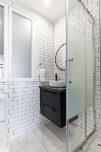 une salle de bain blanche avec un lavabo et un miroir dans l'établissement Chaudron/La Fayette Canal St-Martin Cosy Studio 4P, à Paris