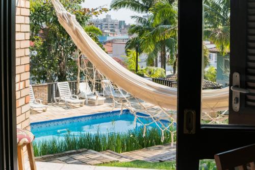 a view of a swimming pool with a hammock next to a window at Pousada Albacora in Bombinhas