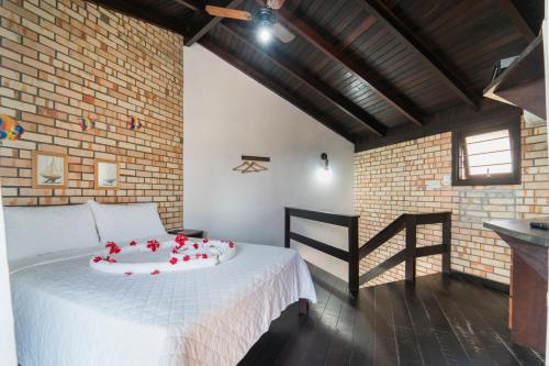 a bedroom with a white bed with red roses on it at Pousada Albacora in Bombinhas