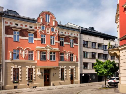 a woman walking a dog in front of a building at Golden Queen Aparthotel in Kraków