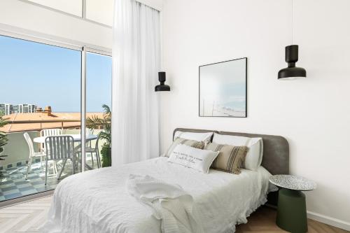 a white bedroom with a bed and a balcony at Sunsets Paradise 2BR with Parking by Beachfront Stay in Herzelia 