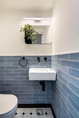 a bathroom with a white sink and blue tiles at Sunsets Paradise 2BR with Parking by Beachfront Stay in Herzelia 