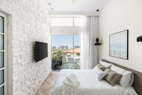 Dormitorio blanco con pared de ladrillo blanco en Sunsets Paradise 2BR with Private Parking, en Herzelia 