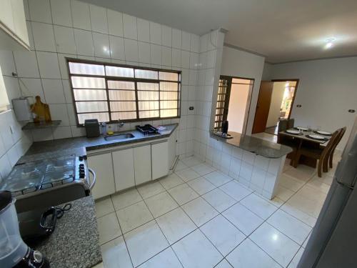 a large kitchen with white tile floors and a table at Casa Roosevelt in Uberlândia