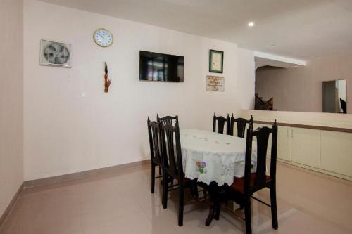 Hotel Wisata Samosir By Helocus في Pangururan: غرفة طعام مع طاولة وكراسي وساعة على الحائط