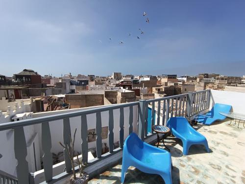 a balcony with blue chairs and a view of a city at Riad Dar Sebta in Essaouira