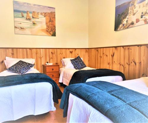 a bedroom with two beds and a painting on the wall at Whispering Woods House in Maryborough