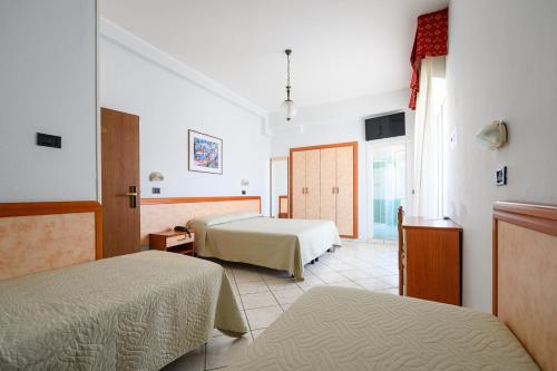 a hotel room with two beds and a window at Hotel de Paris in Lido di Savio