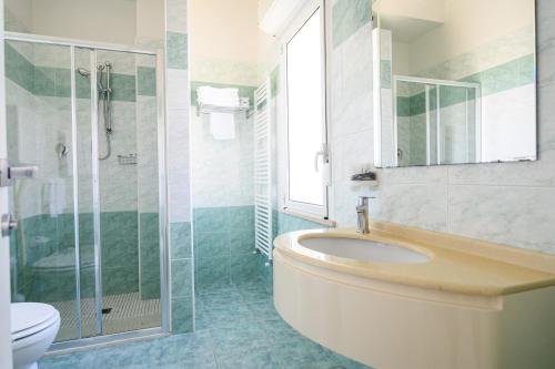 a bathroom with a sink and a shower and a toilet at Hotel de Paris in Lido di Savio