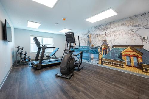 a gym with tread machines and a wall mural at Independence Stay Hotel and Long term suites in Houghton