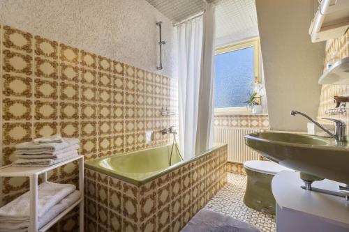 baño con bañera verde y lavamanos en Ferienwohnung am Ps Speicher 