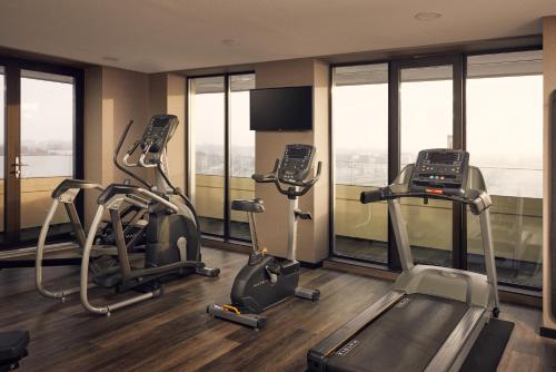 a gym with treadmills and ellipticals in a building with windows at Van der Valk Hotel Groningen-Hoogkerk in Groningen